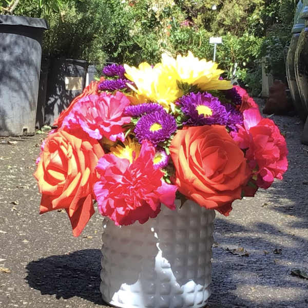 Bright mixed bouquet in a white textured vase with large orange and yellow blooms