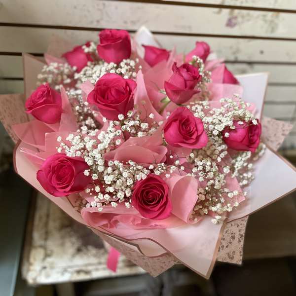 Bouquet of hot pink roses with white baby's breath in pink wrapping