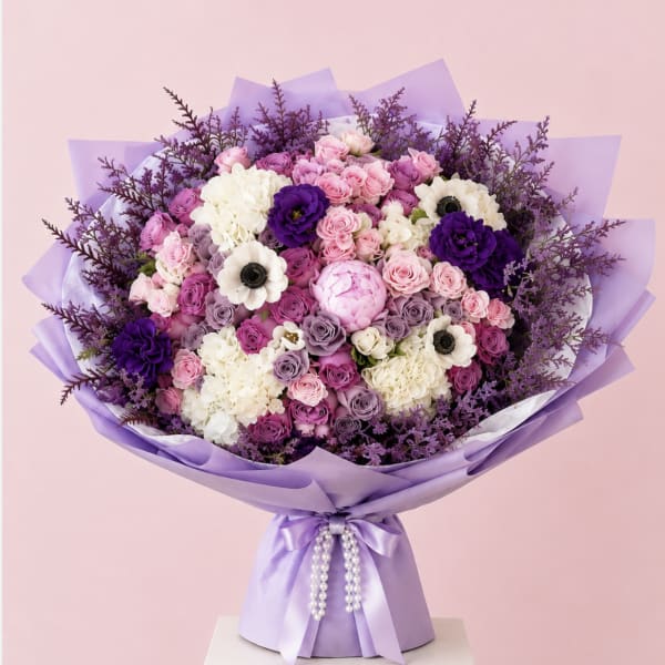 Lavender and pink bouquet with roses, hydrangeas, and white anemones in purple wrap