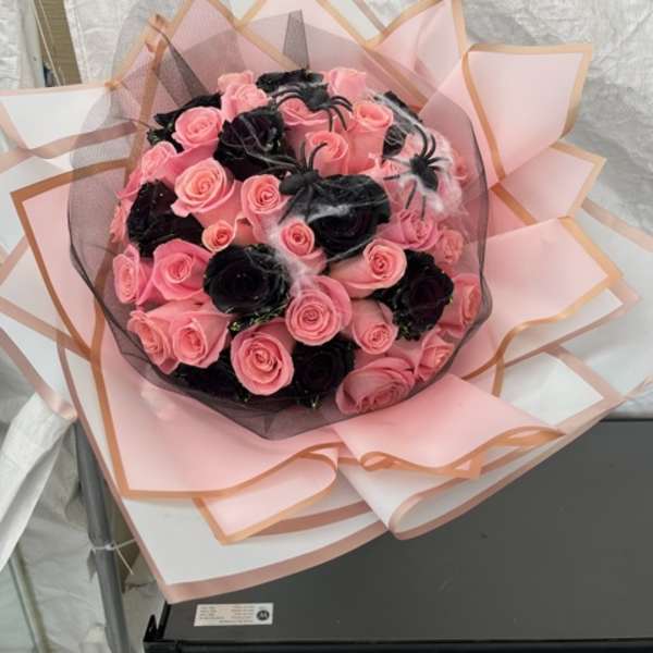 Bouquet of pink and black roses wrapped in pink paper