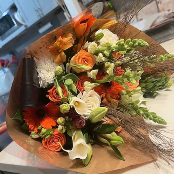 Bouquet of orange and white flowers wrapped in brown paper