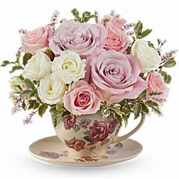 Pink and white roses arranged in a floral teacup