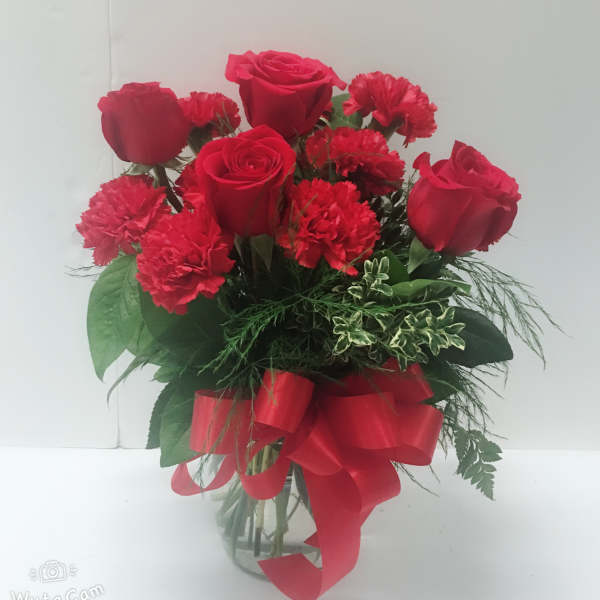 Red roses and carnations in a glass vase with a red ribbon