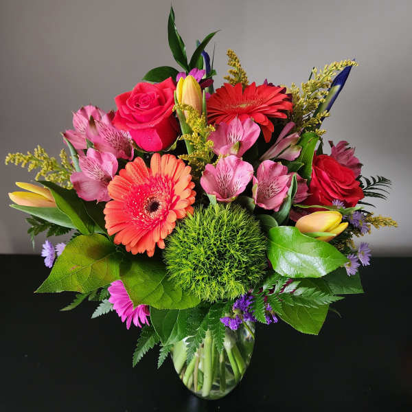 Mixed bouquet of pink and red flowers in a glass vase