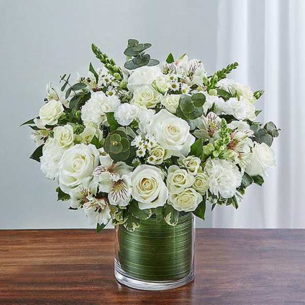 White rose bouquet in a glass vase with mixed greenery