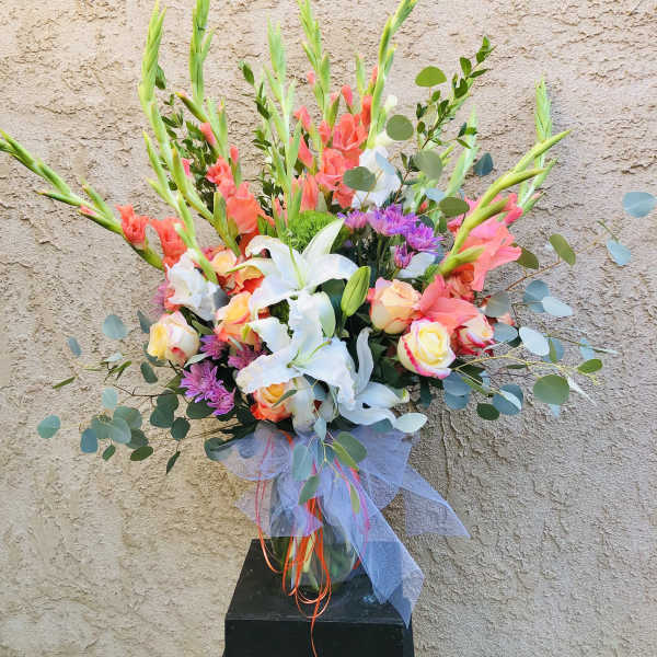 Tall mixed bouquet with lilies, roses, and gladiolus in a glass vase