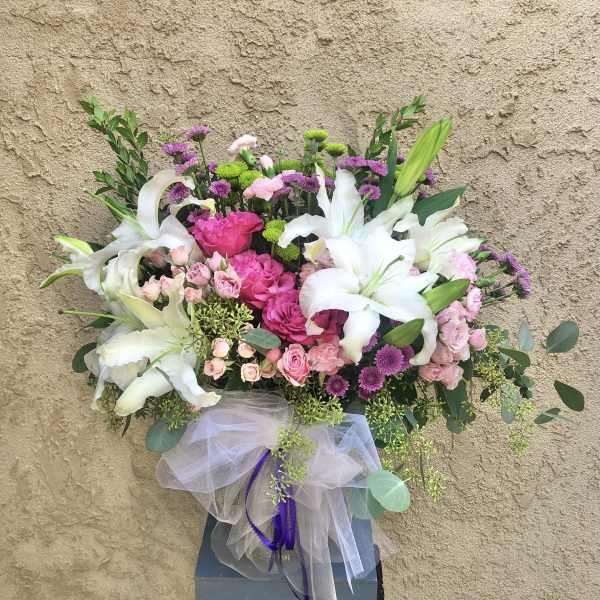 Pink and white floral arrangement in a gray box with tulle ribbon