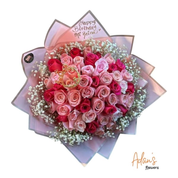 Pink and red rose bouquet wrapped in pastel paper with a birthday topper