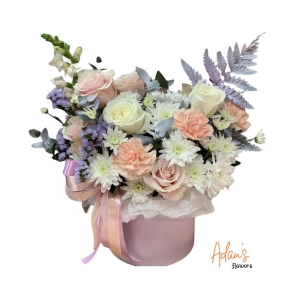 Pastel bouquet of roses, carnations, and white daisies in a pink hatbox