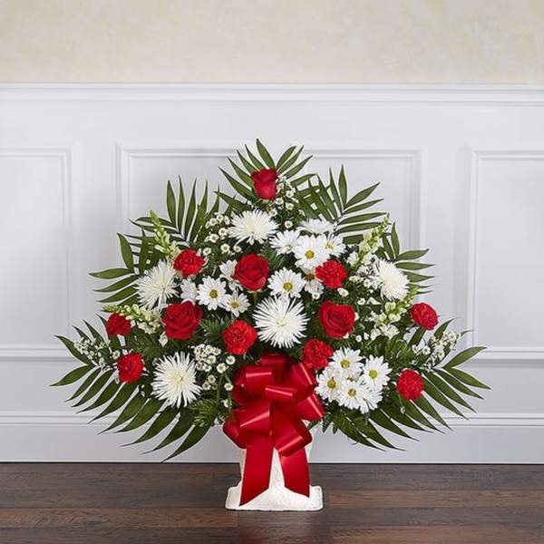 Standing floral spray with red roses, white daisies, and a red bow