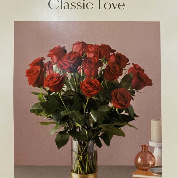Red roses arranged in a clear vase with a gold base