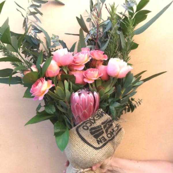 Pink and white bouquet with a large protea in burlap wrap