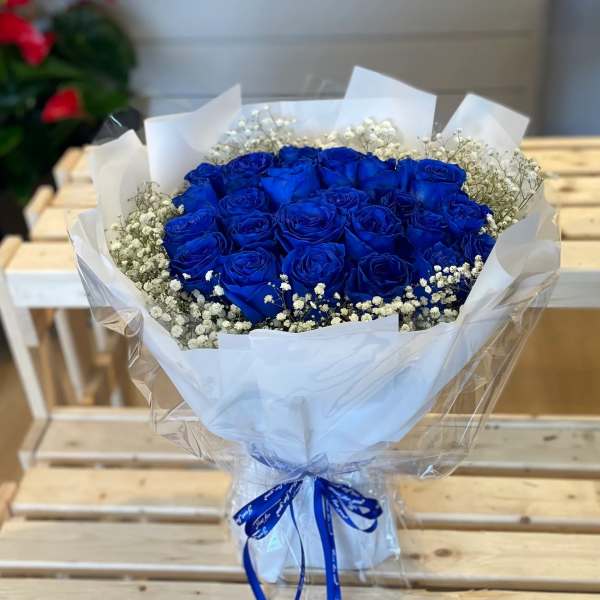 Bouquet of vivid blue roses with white baby's breath in white wrapping