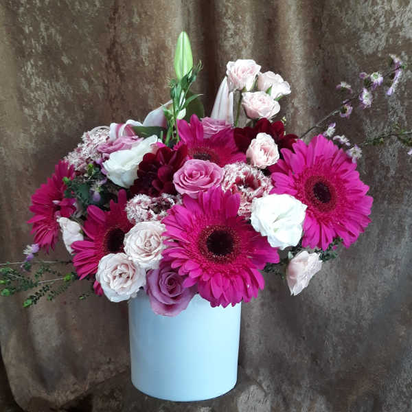 Pink gerbera daisies and roses arranged in a white vase