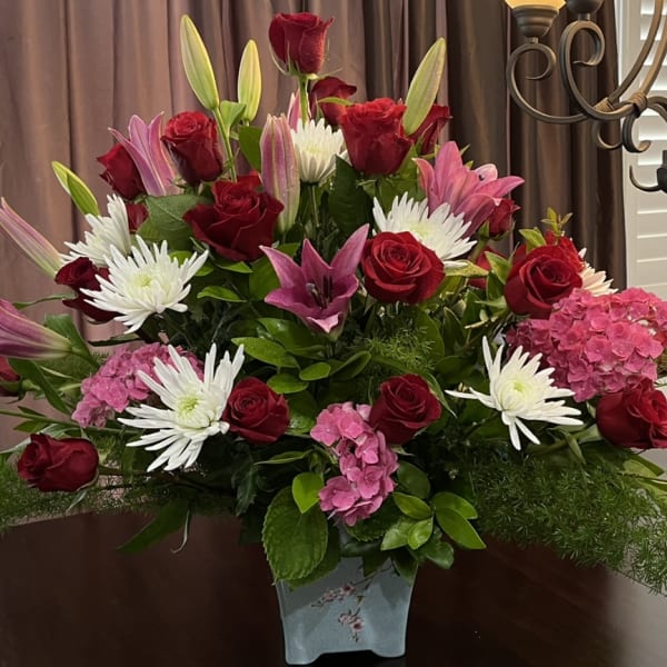 Bouquet of red roses, pink lilies, white daisies, and pink hydrangeas in a vase