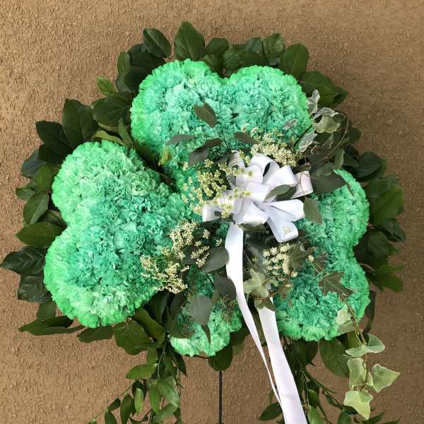 Green carnation wreath with white ribbon and dark foliage