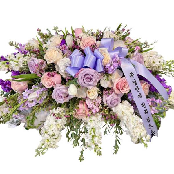Large pastel floral spray with roses and white blooms, tied with a lavender ribbon