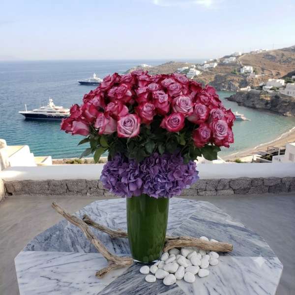 Pink and purple rose arrangement in a tall glass vase
