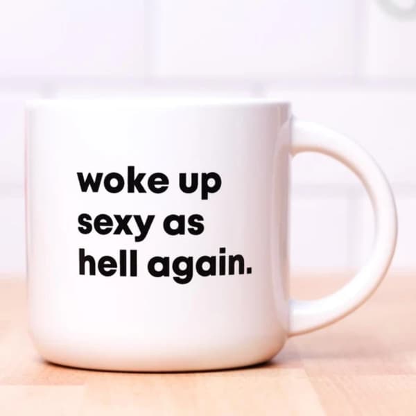 White mug with bold black text reading "woke up sexy as hell again."