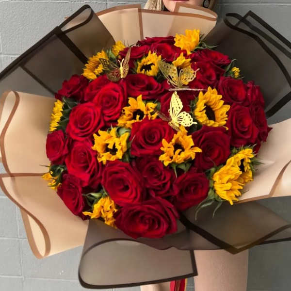 Bouquet of red roses and yellow sunflowers wrapped in tan and black paper