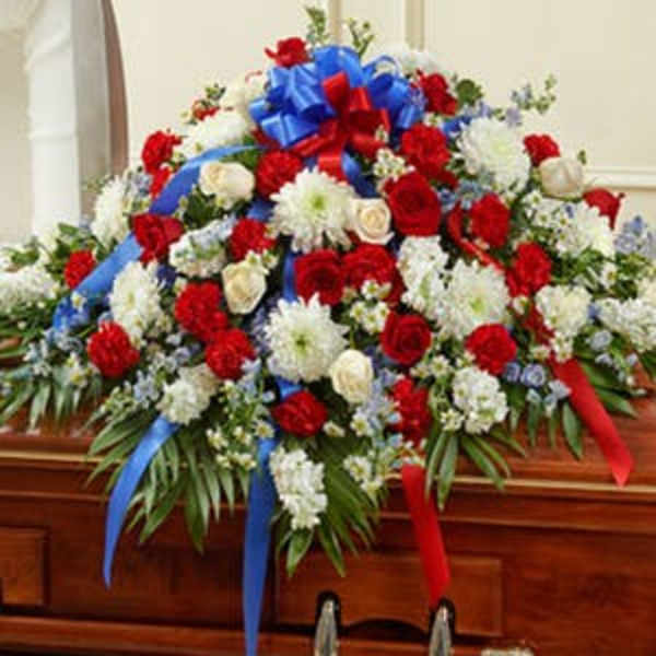 Large red and white floral casket spray with blue and red ribbons