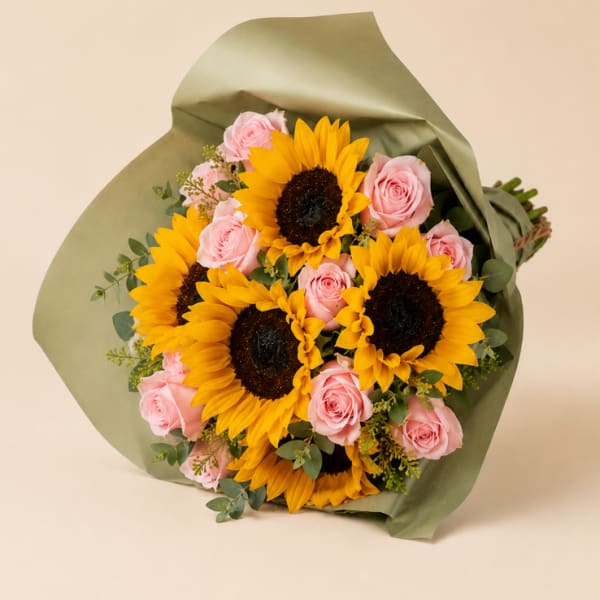 Bouquet of yellow sunflowers and pink roses wrapped in green paper