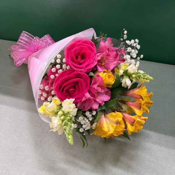 Bouquet of pink roses, pink alstroemeria, and yellow flowers wrapped in pink paper