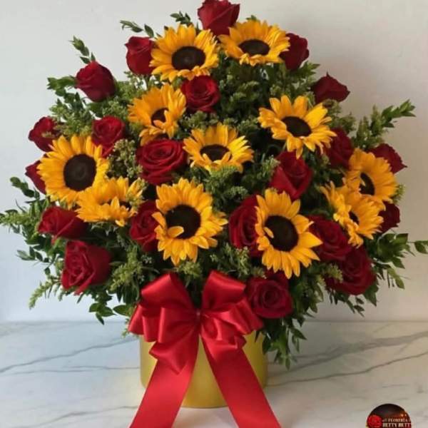 Bouquet of red roses and yellow sunflowers in a gold box with a red ribbon