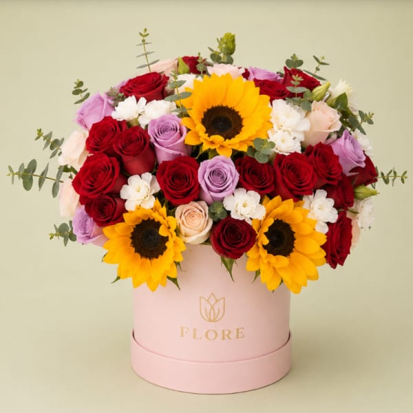 Mixed bouquet of roses and sunflowers in a pink hat box