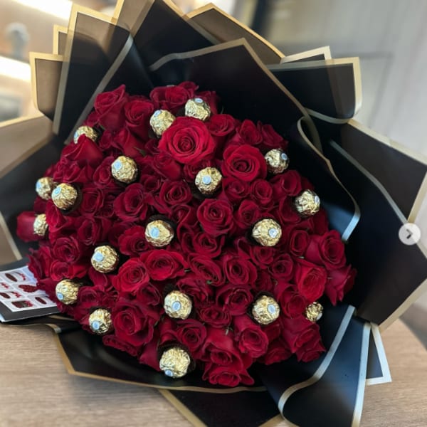 Bouquet of red roses with gold-wrapped chocolates in black paper