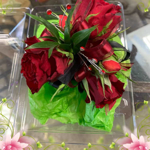 Red rose bouquet with green wrap and ribbon in a clear box