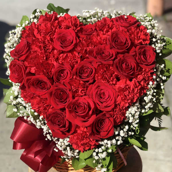 Heart-shaped basket arrangement of red roses and carnations with baby's breath