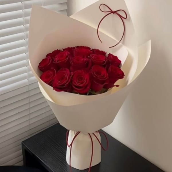 Bouquet of red roses wrapped in cream paper with a ribbon