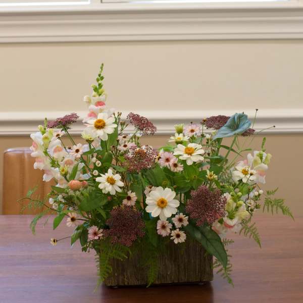 Mixed bouquet of white and pink flowers in a rustic wooden container