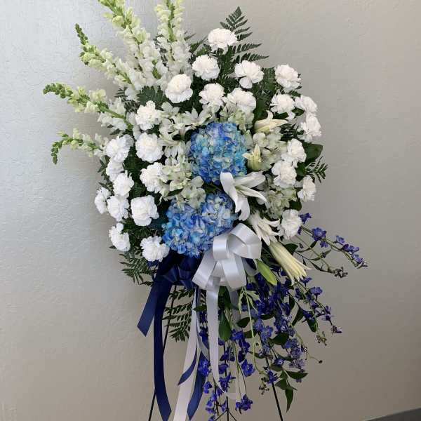 Standing floral spray with white and blue flowers on a black easel
