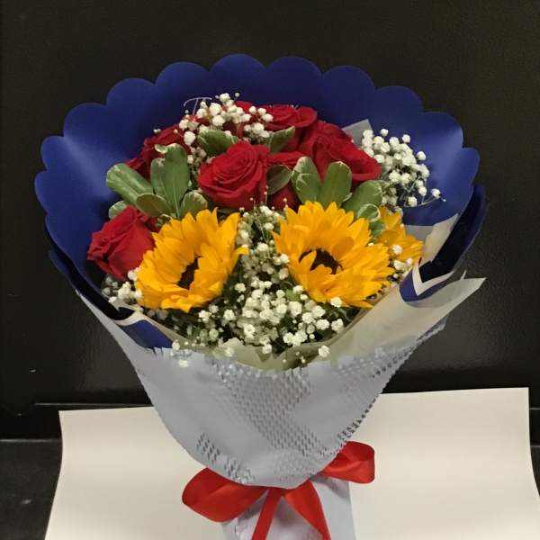 Bouquet of red roses and yellow sunflowers wrapped in blue and white paper
