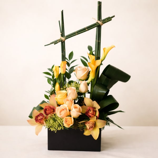 Yellow calla lilies and peach roses in a black box with bamboo accents