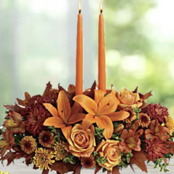 Orange floral centerpiece with two tall taper candles