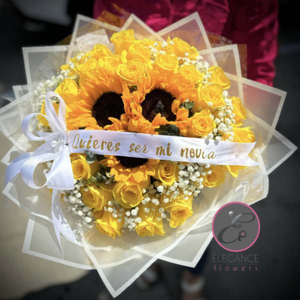 Yellow roses and sunflowers wrapped in clear paper with a white ribbon