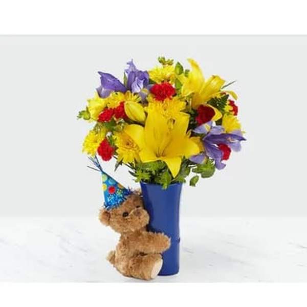 Bright mixed bouquet in a blue vase with a teddy bear attached
