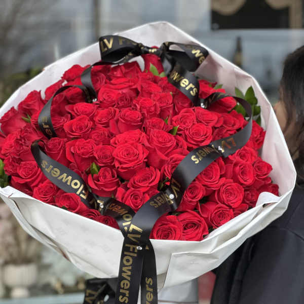 Large bouquet of red roses wrapped in white paper with black ribbon