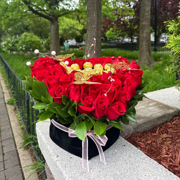 Heart-shaped box of red roses with gold chocolates and a pink ribbon