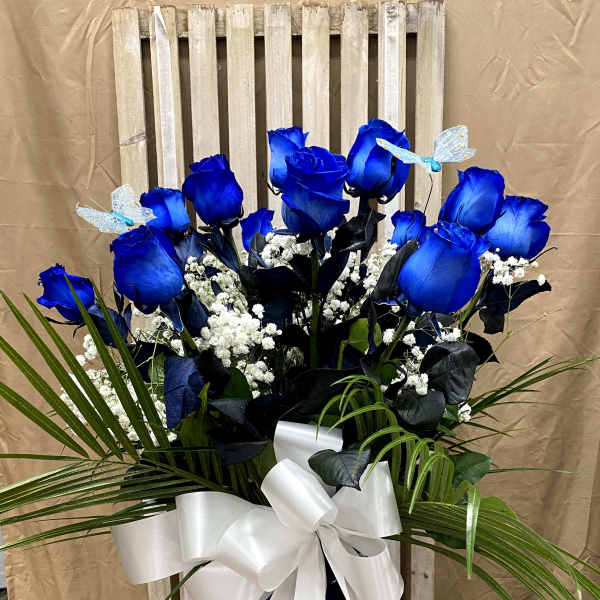 Blue roses in a vase with white baby's breath and a white ribbon