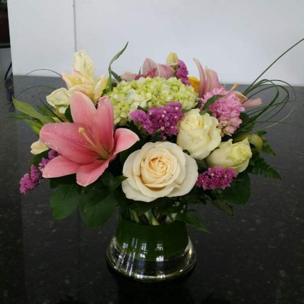 Pink lilies and cream roses in a glass vase