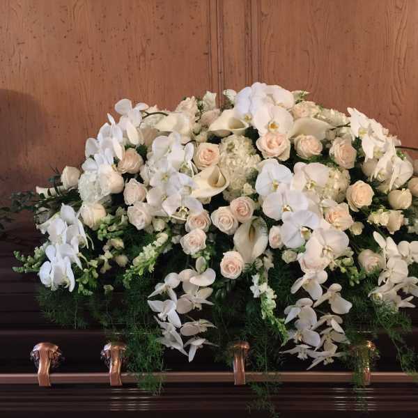 White floral casket spray with orchids, roses, and calla lilies