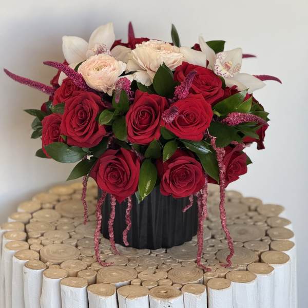 Red and white rose arrangement in a black vase