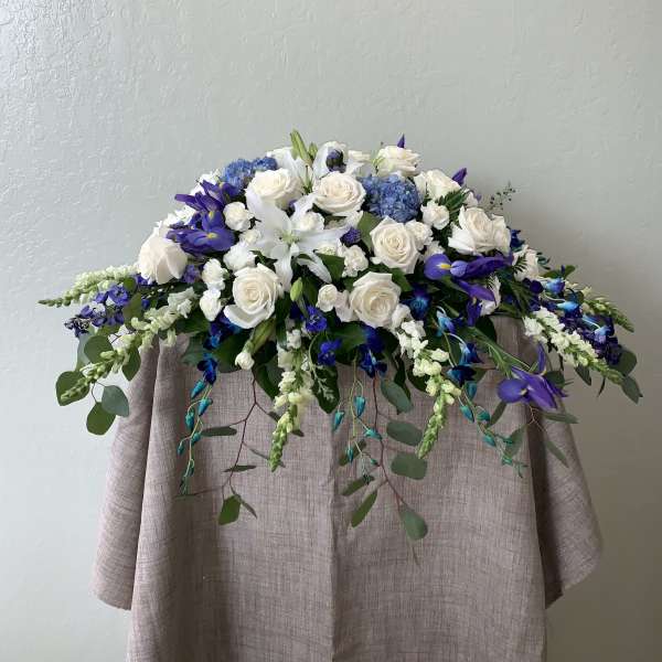 White roses and blue-purple flowers arranged on a draped table.