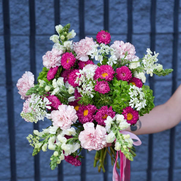Handheld bouquet of pink and white flowers with a pink ribbon