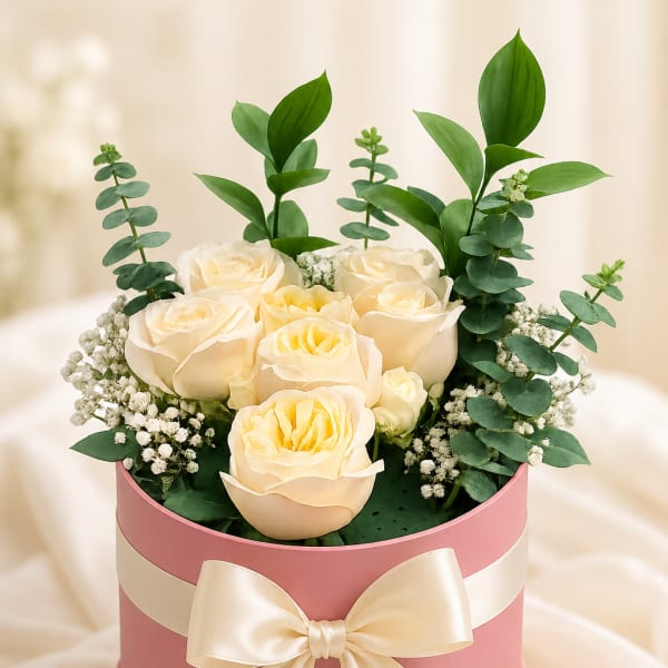 Cream roses in a pink hatbox with a satin bow