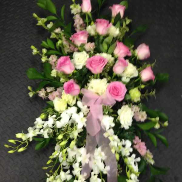 Pink and white floral spray with ribbon on a dark background